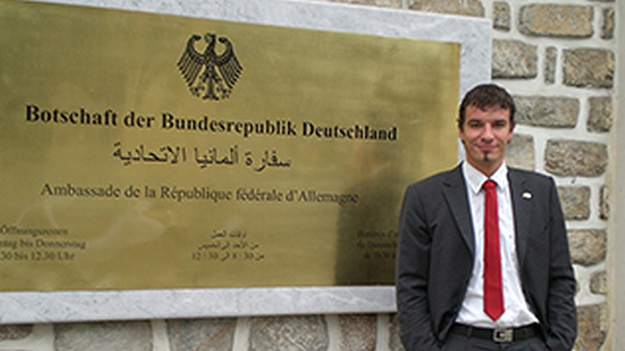 Eine Person steht vor dem Schild "Botschaft der Bundesrepublik Deutschland"