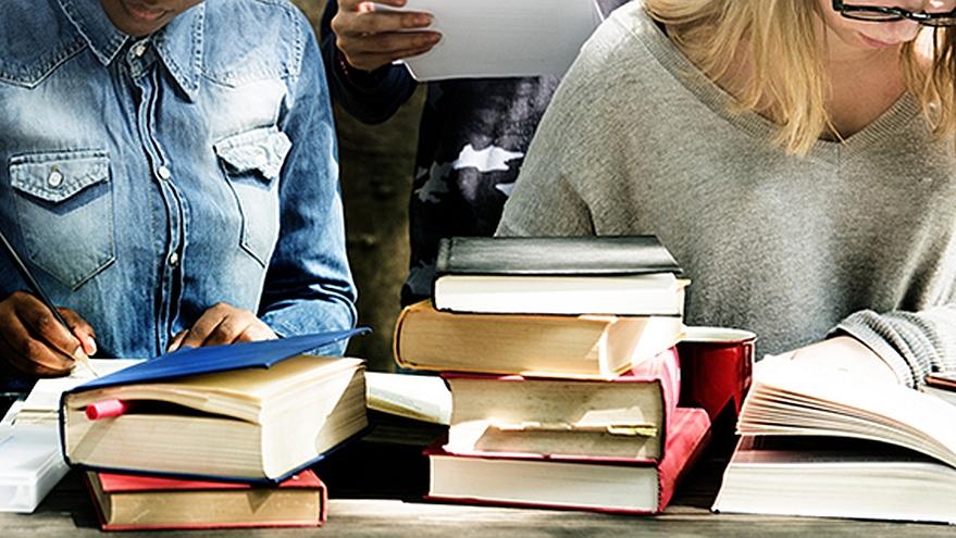 Zwei Personen, Bücher im Vordergrund.